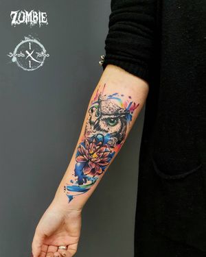 A colorful watercolor design featuring an owl and flower, beautifully created by Dorota on the forearm.