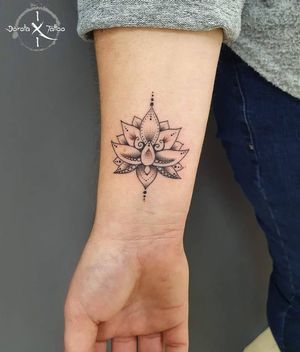Explore the intricate beauty of a blackwork lotus flower design by Dorota, combining geometric and ornamental elements on your forearm.