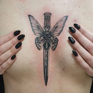 Unique blackwork tattoo featuring an illustrative butterfly and knife design on the chest, by artist Dorota.