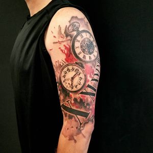 Csaba Sipos' upper arm tattoo features a blackwork clock with Roman numerals and an illustrative quote in a trashpolka style.