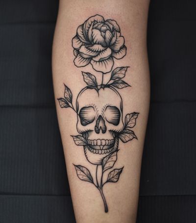 Unique blackwork design by artist Alejandro combining a flower and skull motif on the shin.