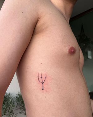 Get a stunning fine line candle and holder tattoo on your ribs, crafted by the talented artist Sofi. Perfect for a touch of illustrated elegance.