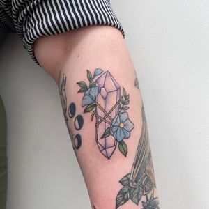 Beautiful forearm tattoo by Rachel Angharad featuring a detailed flower and crystal design.