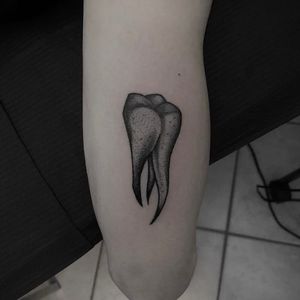Unique blackwork design of teeth by Shasza, creatively placed on upper arm for a bold statement.