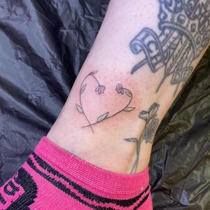 Delicate heart and sprig tattoo on the ankle by artist Rachel Angharad. Perfect for adding a touch of elegance to your body art collection.
