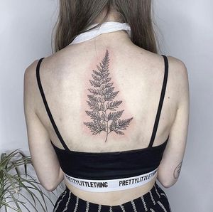 A beautiful fine line design featuring a tree, flowers, sprigs, and leaves by talented artist Rachel Angharad. Perfect for those looking for a detailed and elegant back tattoo.