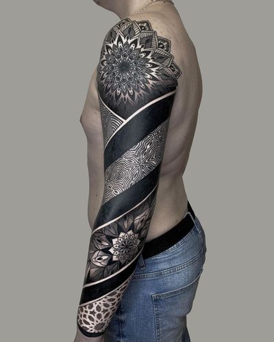 Stunning blackwork and dotwork sleeve tattoo featuring ornamental geometric patterns and delicate floral motifs by artist Nastya.