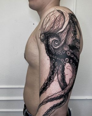 Fine line illustrative upper arm tattoo by Nastya, featuring a detailed octopus design surrounded by intricate patterns.