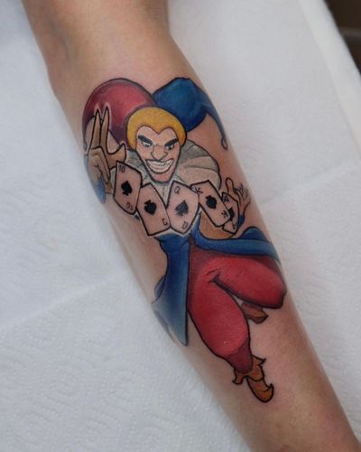 Vibrant new school tattoo featuring a joker card motif, done by the talented artist Denis on the forearm.