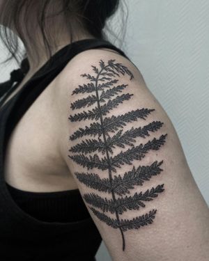 Beautiful blackwork tattoo of a tree and leaf on the upper arm, created by artist Nastya. Captivating and intricate design.