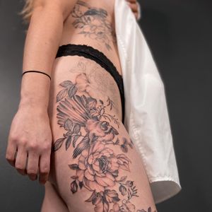 Beautiful blackwork upper leg tattoo featuring a stunning bird and flower design by talented artist Liliia.