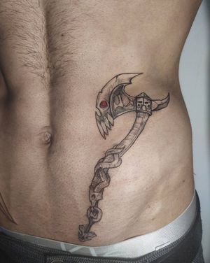 Impressive blackwork piece by Maryna on ribs featuring a snake, skull, and axe motif for a bold and edgy look.