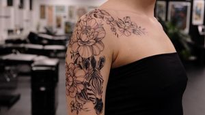 Stunning upper arm tattoo combining a zebra and flower in a bold blackwork style by artist Liliia.
