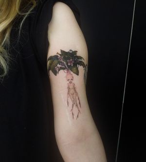 This illustrative tattoo by Maryna features a beautiful blend of flowers, a man, and a woman, creating a romantic and artistic design on the upper arm.