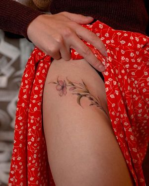 Beautiful illustrative flower tattoo on upper leg by Liliia featuring intricate fine line details.