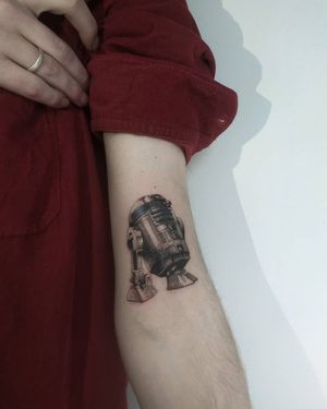 Get the iconic droid inked on your upper arm with this stunningly detailed and illustrative tattoo by talented artist Maryna. Embrace your love for sci-fi and Star Wars with this unique piece.