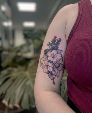 A stunning blackwork and illustrative tattoo on the upper arm featuring a beautiful combination of flowers and fruit, created by the talented artist Liliia.