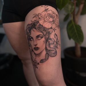 Bold blackwork tattoo of a snake, medusa, flower, and woman, expertly done by Liliia. A stunning illustrative masterpiece.