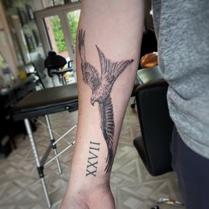 Stunning black and gray tattoo of a majestic bird of prey by Emma Raine Tattoo, featuring intricate lettering details.