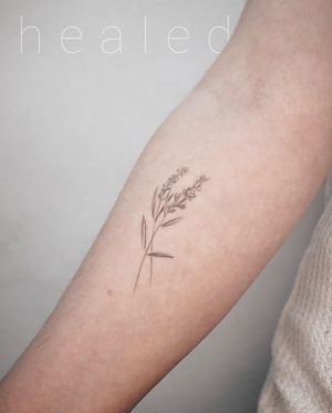 Elegant illustrative tattoo by George Francis, featuring a delicate flower sprig design on the forearm.