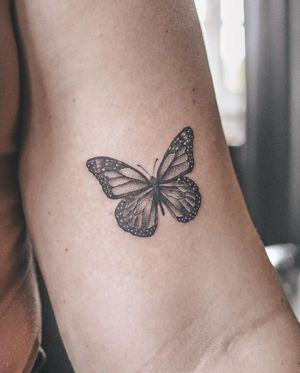 Blackwork butterfly design on upper arm by artist George Francis, a stunning and timeless piece of body art.