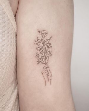 Beautifully detailed tattoo by George Francis, featuring a delicate flower and hand design on the upper arm. A perfect blend of fine line and illustrative styles.