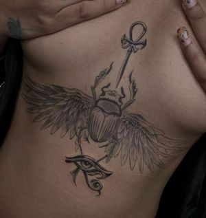 Unique blackwork tattoo on sternum by artist Angel Chavez featuring Horus eye, beetle, and wings motif.