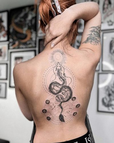 Discover the beauty of a fine line, illustrative tattoo on your back by Alisa Hotlib. This unique design combines a sun, dragon, and ornamental patterns.