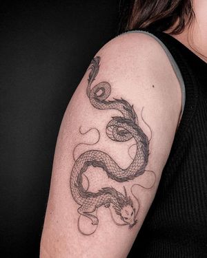 Elegant and detailed dragon design on upper arm, created with fine line technique by talented artist Alisa Hotlib.