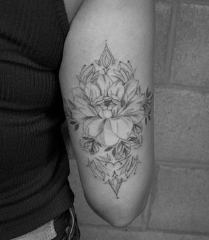 Blackwork and fine line flower tattoo by Angel Chavez, featuring intricate illustrative details on the upper arm.