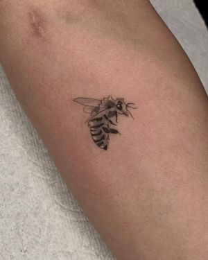 Bold blackwork bee tattoo on the forearm by Angel Chavez. Unique and eye-catching design.