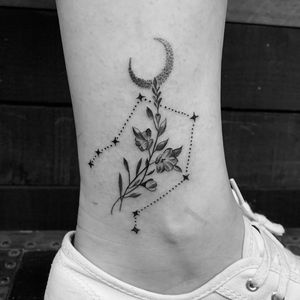 Get a stunning blackwork and dotwork ankle tattoo featuring a moon, flower, and sprig. Designed by the talented Angel Chavez.