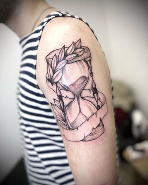 Beautiful blackwork design on upper arm featuring a flower, leaf, and hourglass, done by Ruslan.