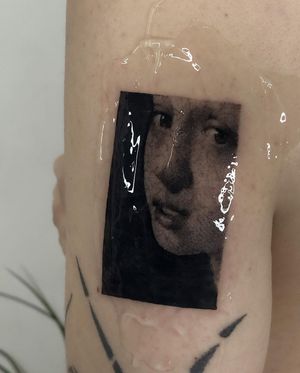 Beautiful blackwork upper arm tattoo of a girl, by Toma, combining realism and illustrative style.