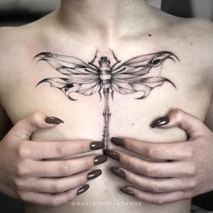 A striking blackwork illustrative tattoo of a dragonfly on the chest, expertly done by the talented artist Ruslan.