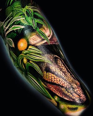 Experience the intricate details of a snake intertwining with a leaf in this stunning illustrative tattoo by Mika.