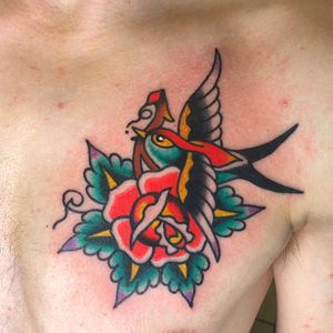 Beautiful traditional chest tattoo featuring a bird and flower motif, inked by the talented artist Nick Osbourn.