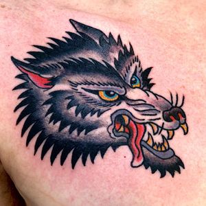 This illustrative wolf chest tattoo by Jason Fancher combines traditional style with bold design.