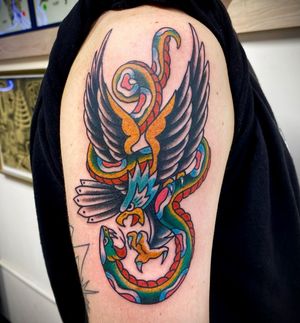 Impressive upper arm tattoo featuring a snake and eagle in traditional illustrative style by Sasha Ignarski.