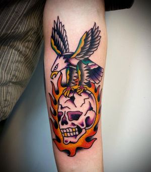 Incredible traditional tattoo by Sasha Ignarski featuring a fierce eagle, skull, and dynamic flames. Bold and striking design!