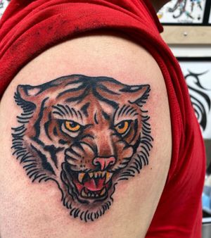 Capture the fierce elegance of a tiger with this illustrative traditional tattoo by Jason Fancher on your upper arm.