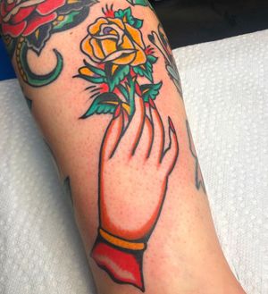 Beautiful arm tattoo by Nick Osbourn featuring a traditional style flower and hand motif.