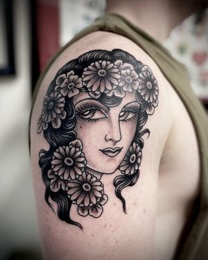Stunning blackwork upper arm tattoo of a beautiful woman intertwined with intricate flowers, by Sasha Ignarski.