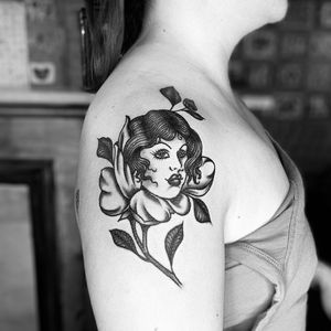 Beautiful blackwork tattoo of a woman intertwined with a flower, skillfully done by Kat Freedman on the upper arm.