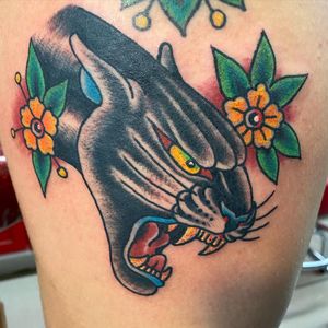 Traditional style tattoo featuring a fierce panther and delicate flower design, expertly done by Jason Fancher on the upper leg.