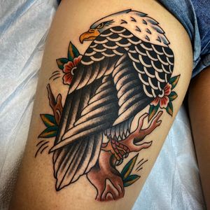 Get inked with a stunning traditional style tattoo of an eagle and flower on your upper leg by Sasha Ignarski.