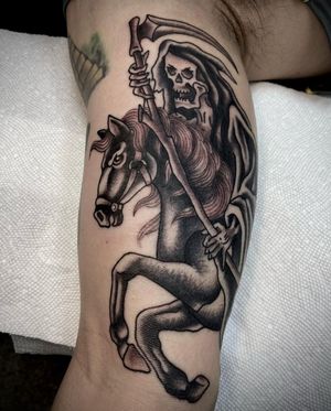 Unique blackwork tattoo on the upper arm featuring a grim reaper, horse, and scythe by Sasha Ignarski. A powerful symbol of death and rebirth.