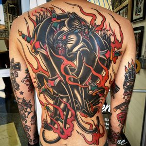 A striking traditional style tattoo by Philip LaRocca featuring a fierce panther, a sharp sword, and dynamic flames on the back.