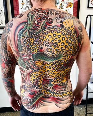 Experience the thrill of the wild with an illustrative traditional tattoo featuring a leopard, alligator, and waves by Philip LaRocca.