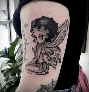 Get inked with a stunning blackwork tattoo of Betty Boop, a fierce woman with wings, by the talented artist Sasha Ignarski.
